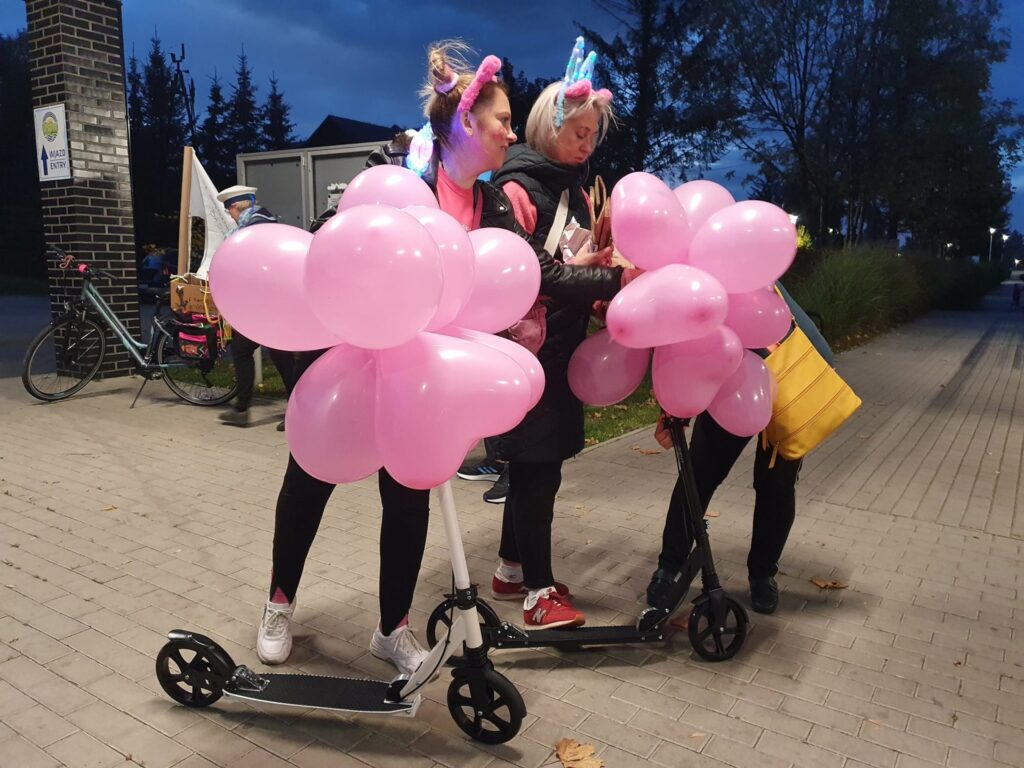kobiety na hulajnogach z różowymi balonami