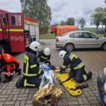 strażacy przekładają poszkodowanego zawiniętego w folię na nosze