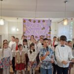 grupa dzieci, w tle napis na ścianie dzień seniora