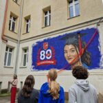 uczniowie z tyłu, widok na mural i dyrektor