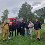 samorządowcy, strażacy i policja stoją razem na trawie