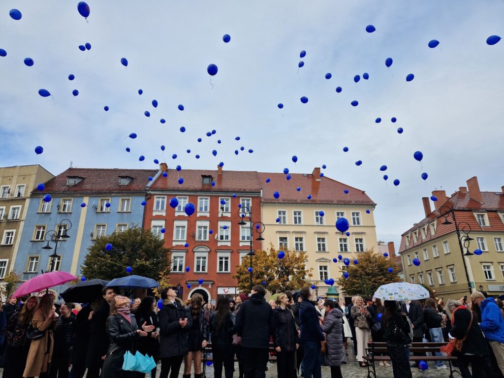 ludzie na rynku, w powietrzu niebieskie balony