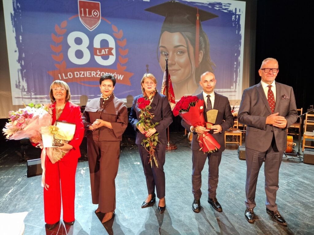 starosta, wicestarosta, dyrektor ILO, dyrektor wydziału edukacji i przewodnicząca komisji edukacji stoją na scenie z kwiatami