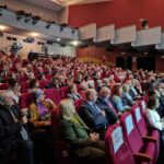 widok z boku na całą salę w kinoteatrze i siedzących gości