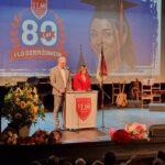 przemówienie dyrektor ILO, obok stoi nauczyciel, w tle obraz muralu