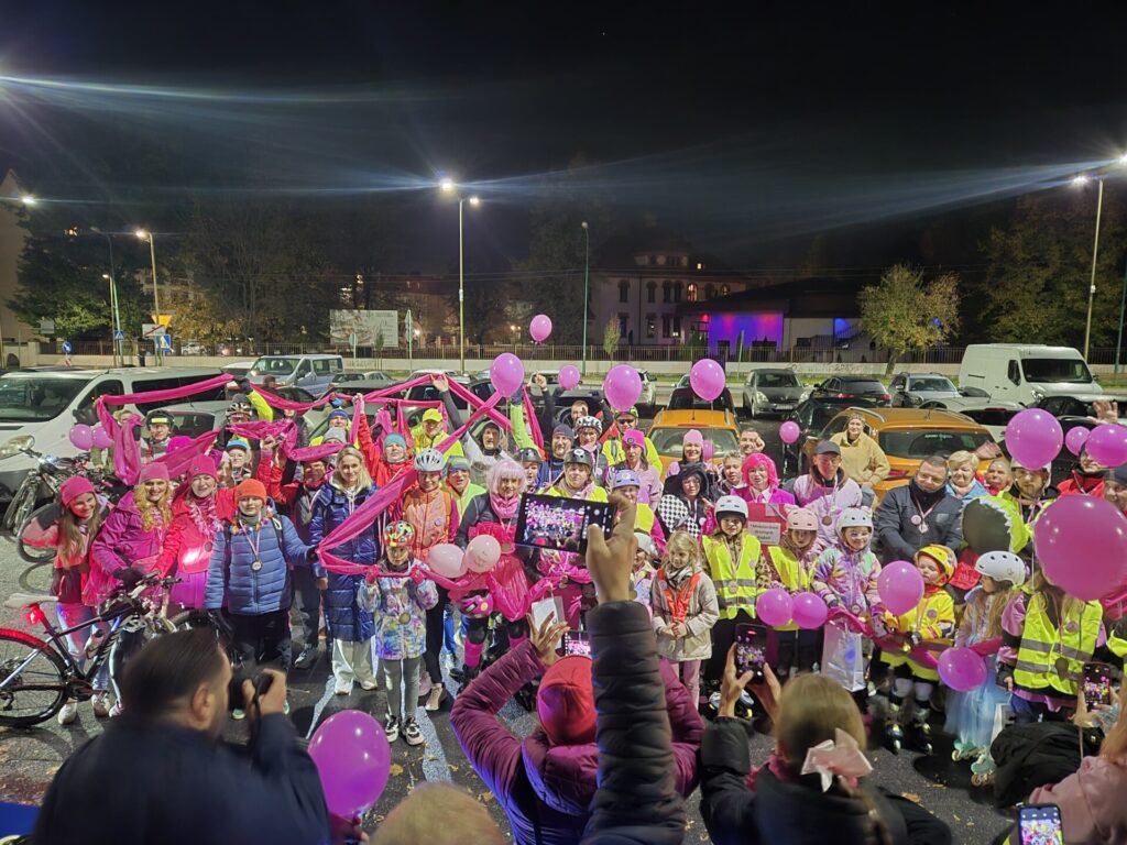 zdjęcie grupowe, uczestnicy trzymają różowe balony i różową szarfę