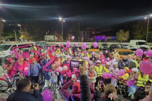 zdjęcie grupowe, uczestnicy trzymają różowe balony i różową szarfę