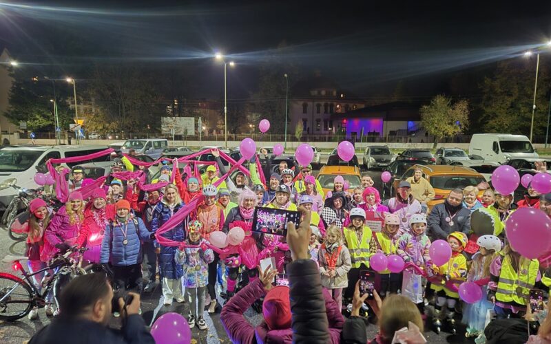 zdjęcie grupowe, uczestnicy trzymają różowe balony i różową szarfę