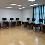 sprzęt komputerowy i biurka w pracowni informatycznej