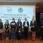 kilka osób stoi przed tablicą z napisem