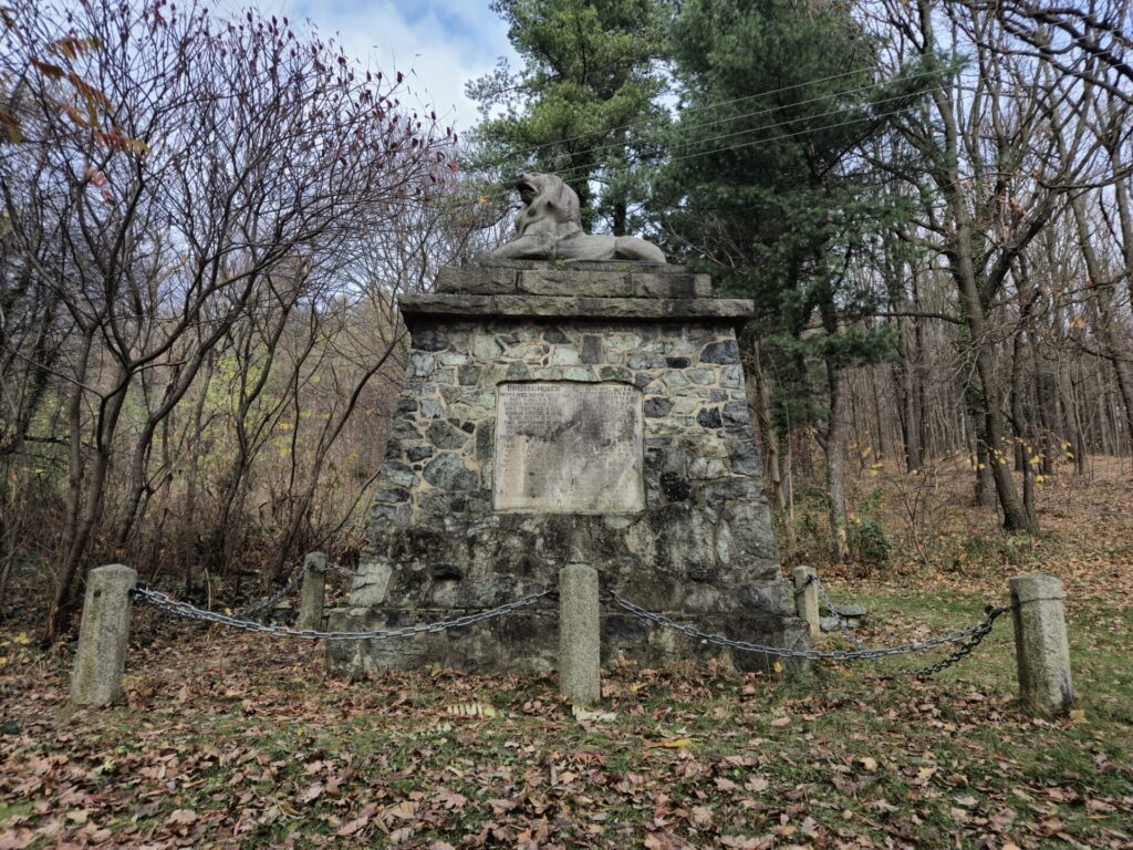 pomnik ogrodzony łańcuchem, w tle drzewa