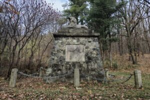 pomnik ogrodzony łańcuchem, w tle drzewa