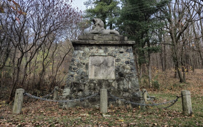 pomnik ogrodzony łańcuchem, w tle drzewa