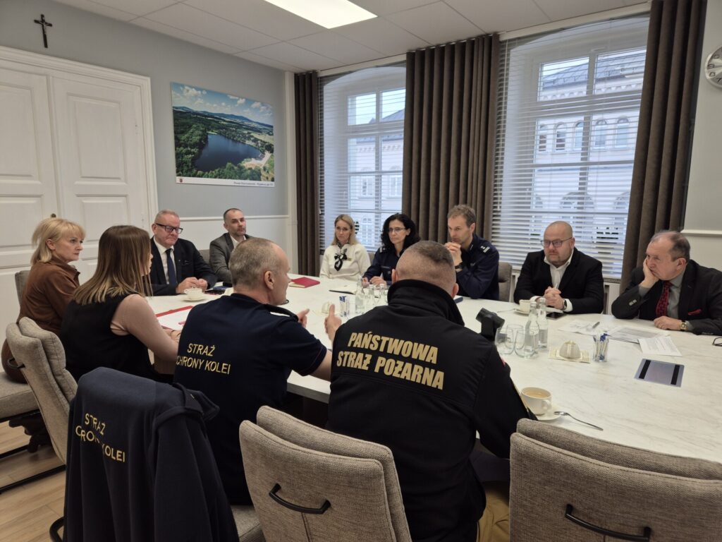 uczestnicy PZZK siedzą przy stole, komendant straży i SOK tyłem