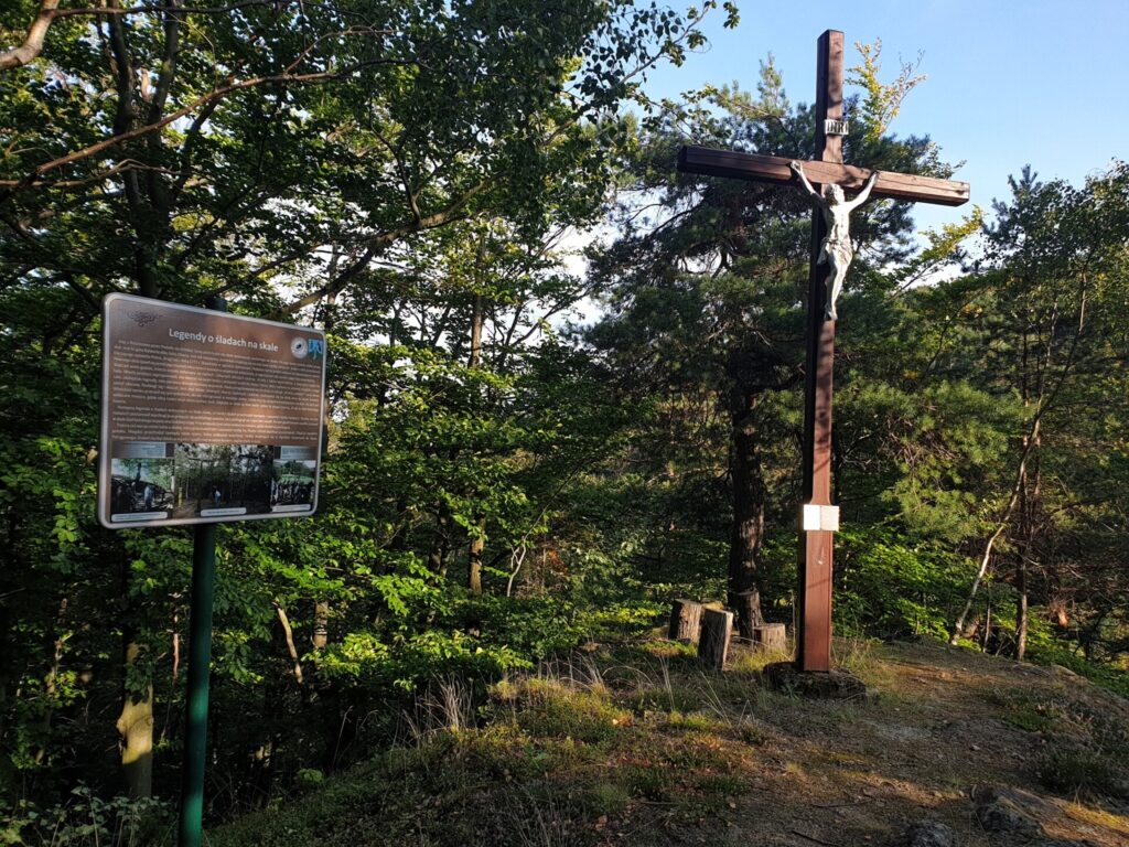 krzyż na górze, obok tablica, w tle drzewa