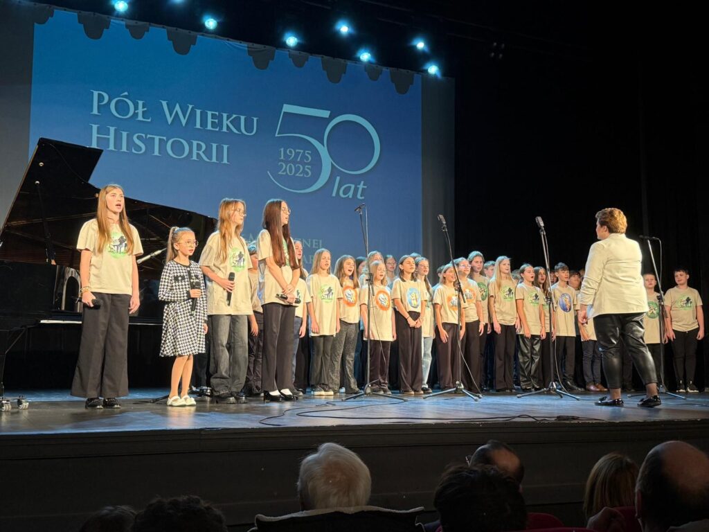 dzieci i młodzież na scenie w dużej grupie śpiewają