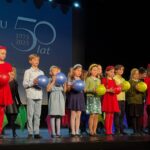 dzieci ubrane na kolorowo na scenie z balonami