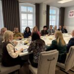 widok w stronę okien na siedzących przy stole