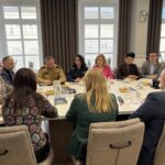 widok w stronę okien, uczestnicy spotkania siedzą przy stole