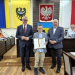 starosta Grzegorz Kosowski, przewodniczący rady Jacek Grzebieluch i zwycięzca konkursu z dyplomem