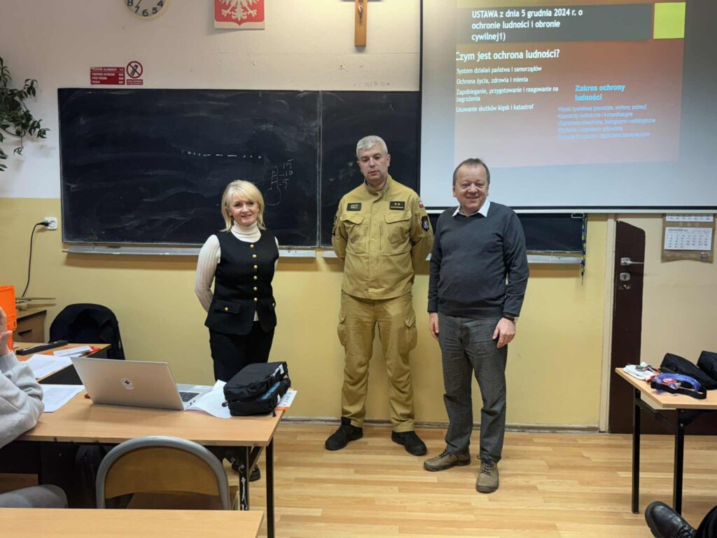 przedstawiciel straży pożarnej, dyrektor wydziału bezpieczeństwa i dyrektor zs 2 stoją przy tablicy