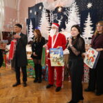 ludzie stoją ze Świętym Mikołajem, trzymają prezenty