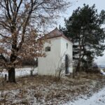 kapliczka z boku i lekko z frontu, wokół drzewa