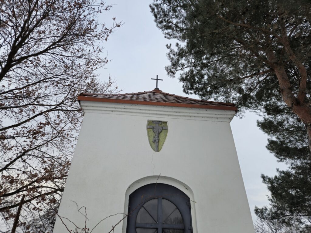 zbliżenie na frontową ścianę zewnętrzną kapliczki, na płaskorzeźbę