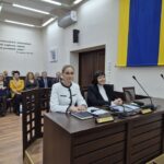 sekretarz i radca prawny siedzą przy stole, w tle zaproszeni goście