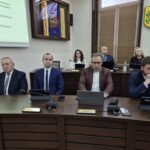 4 radni siedzą przy stole, za nimi 3 radnych