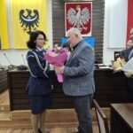 przewodniczący wręcza kwiaty komendant, obok stoi wicestarosta ze statuetką