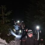 ludzie idą po ścieżce z latarkami