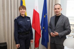 komendant policji i wicestarosta stoją razem na tle flag