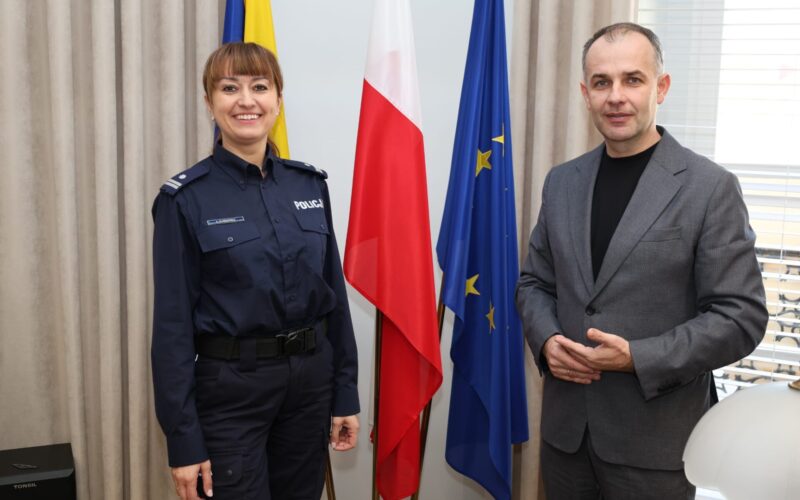 komendant policji i wicestarosta stoją razem na tle flag