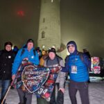 wspólne zdjęcie wicestarosty, posła i szefa dzierżoniowskiego sztabu wośp z flagą na tle wieży