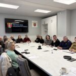 widok na uczestników, w tle tablica z herbem powiatu