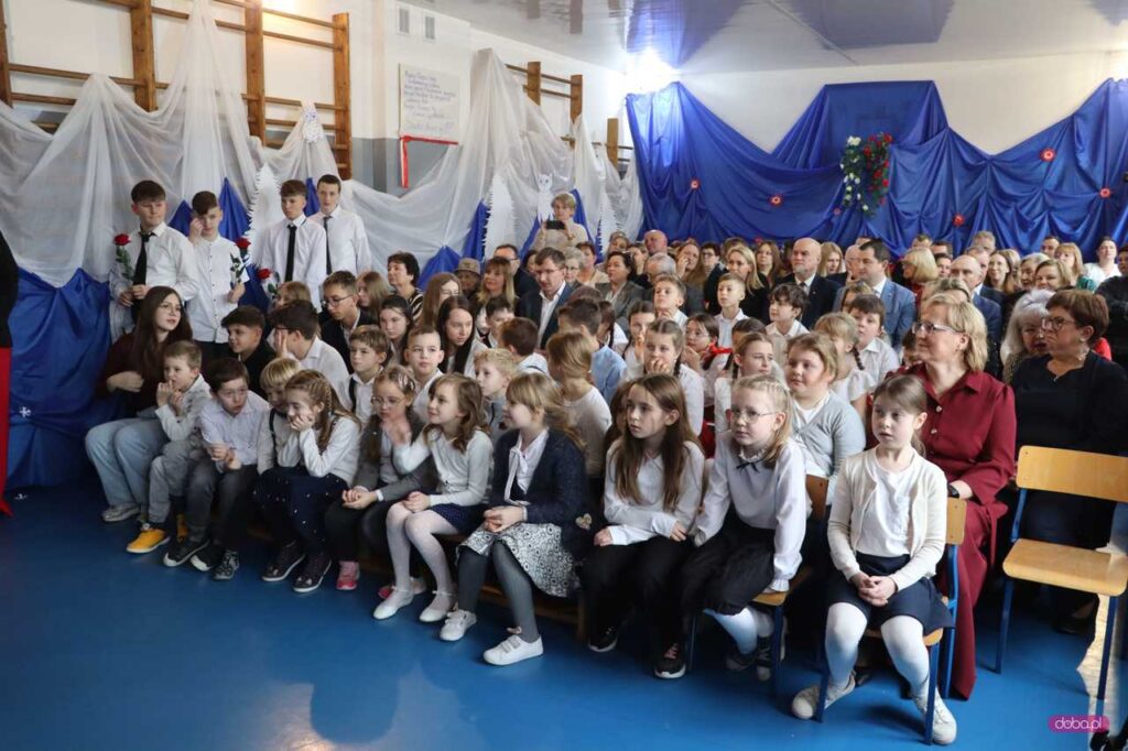 dzieci i zaproszeni goście siedzą razem na krzesłach na sali