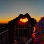 zdjęcie przedstawia wschód słońca w środku serca z dłoni