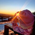 zdjęcie przedstawia słońce w środku serca z dłoni, z widokiem na góry