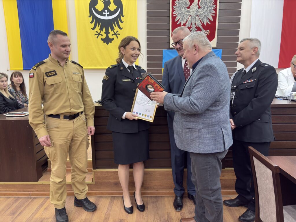 przewodniczący Jacek Grzebieluch i starosta Grzegorz Kosowski wręczają statuetkę Beacie Kuriacie-Świderskiej