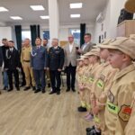 młodzież w strojach strażackich, w tle samorządowcy i komendanci