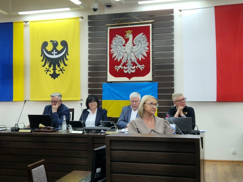 dyrektor PCPR Dzierżoniów przemawia, w tle prezydium rady