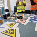 pracownice sanepidu w odblaskowych kamizelkach pokazują dzieciom znaki, na stole znaki