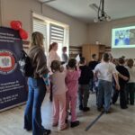 grupa dzieci tyłem, na ekranie wyświetlone 2 zdjęcia