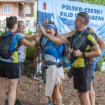 grupa ludzi przybija piątki na tle ścianki rajdu
