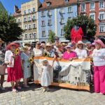 grupa kobiet w kapeluszach z banerem Dzienny Dom Senior +, zdjęcie wspólne z posłem i wicestarostą
