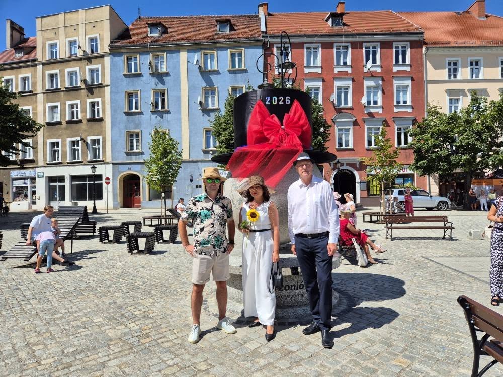 wspólne zdjęcie wicemarszałek, posła i wicestarosty przed globusem z nałożonym kapeluszem