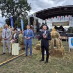wicestarosta i wójt ze starościną i starostą dożynek stoją na tle wieńców i sceny