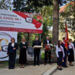 grupa osób pod banerem z nazwą szkoły