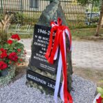 odsłonięty obelisk kwiatami i wstęgami